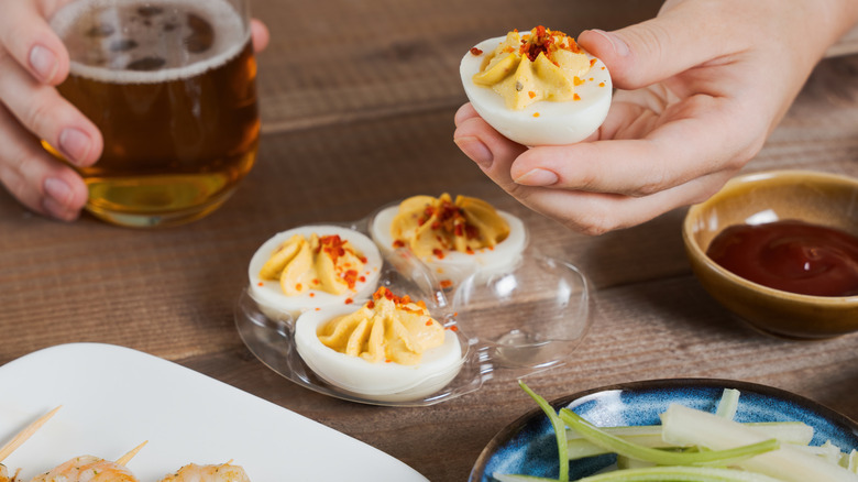 A dinner guest chooses a deviled egg from a serving tray
