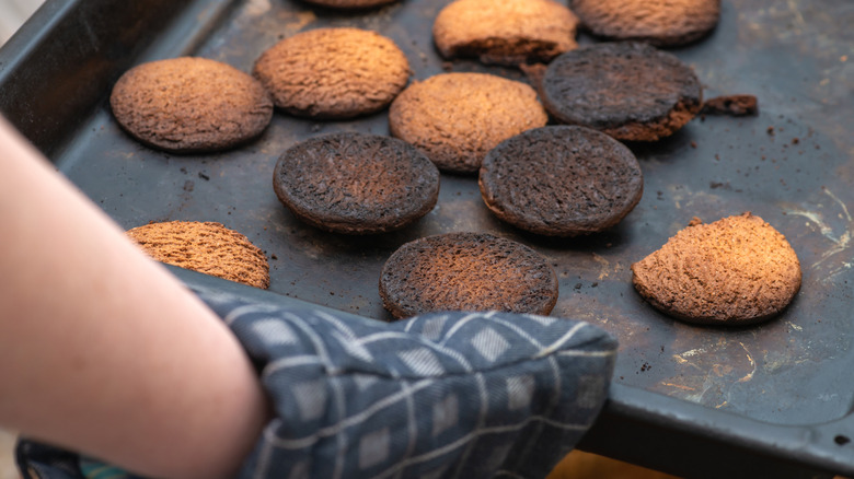 A home baker holds a tray of burned cookies