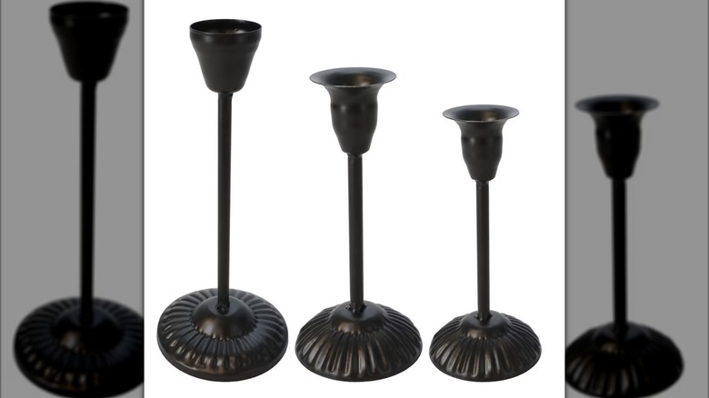 A set of three black iron candle holders in graduating sizes