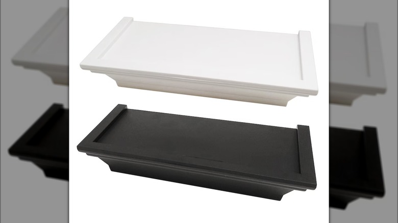 A white floating shelf with crown molding is shown above a similar black shelf