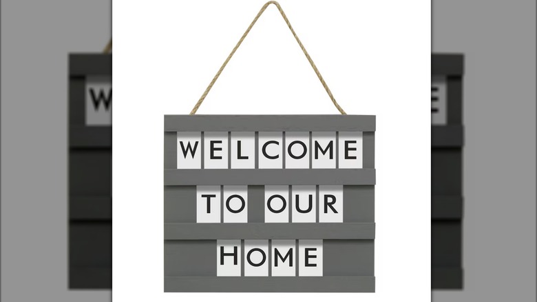 A gray sign with customizable letters and thin rope for hanging