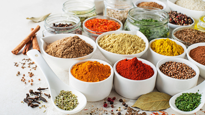 Array of colorful herbs and spices in small ceramic and glass dishes