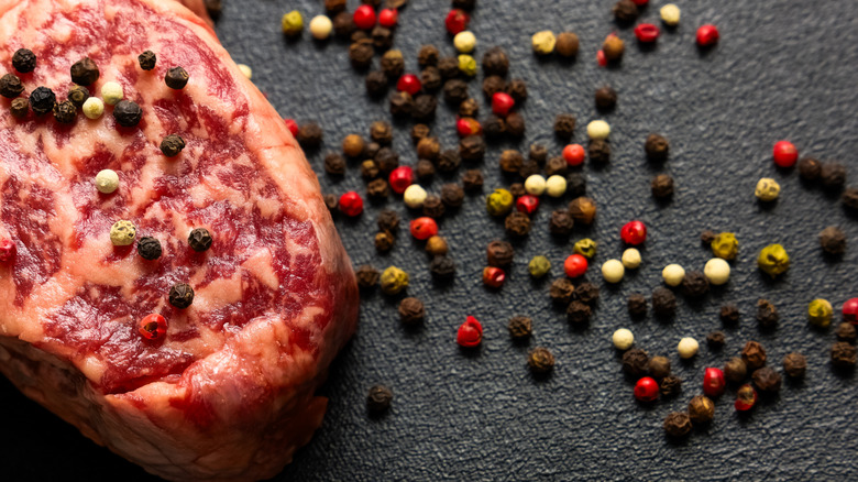 Raw steak with various colors of fresh peppercorns