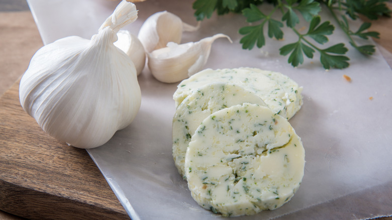 Slices of garlic compound butter with heads of garlic