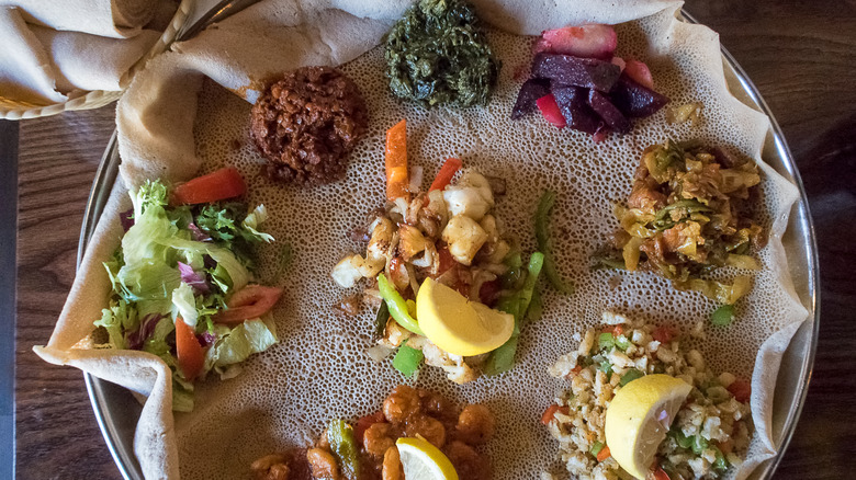 Round of injera topped with varied Ethiopian dishes