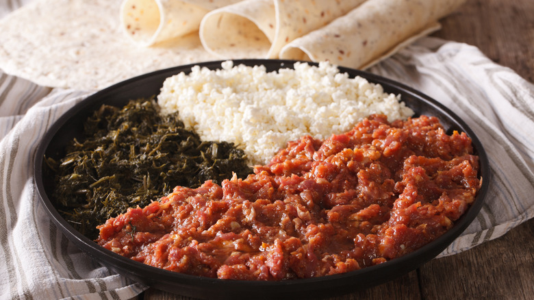 Kitfor with cheese, greens, and injera