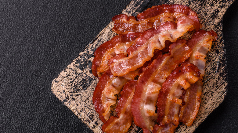 Crispy bacon strips on a wooden cheese board
