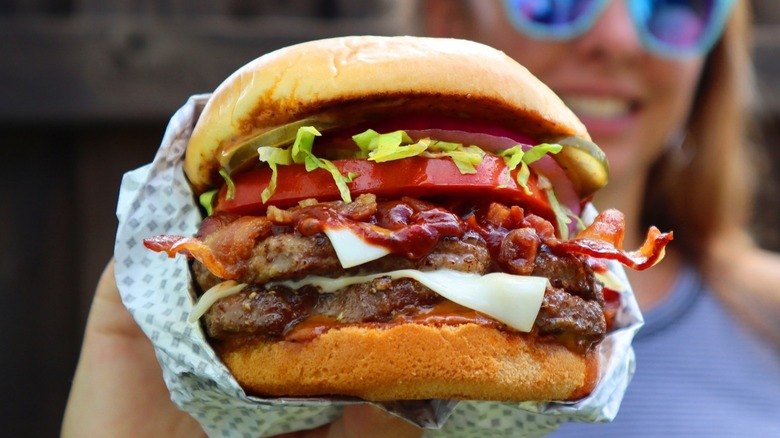 A hand holding the Smoky BBQ Bacon Buford Triple