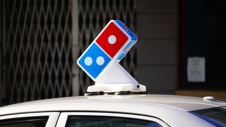 Domino's logo atop a pizza delivery car