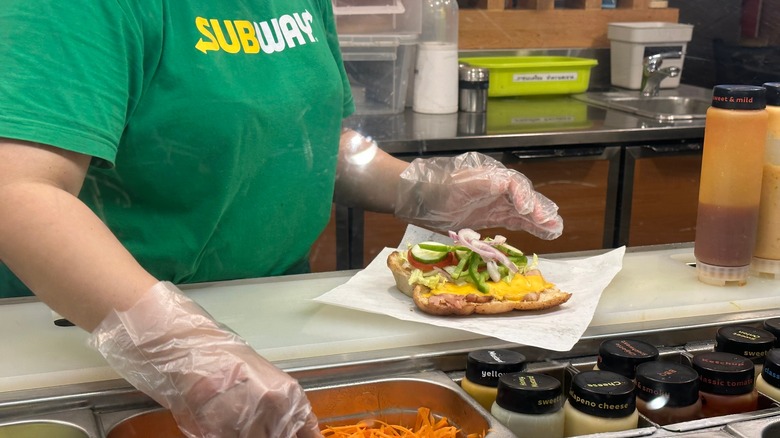 Sandwich artist preparing a Subway sub