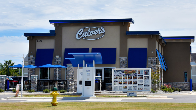 The exterior of Culver's with blue umbrellas and order kiosks at the front