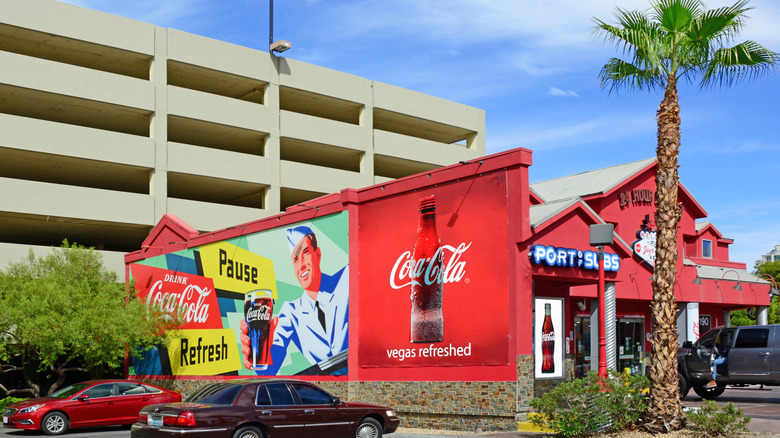 The exterior of Port of Subs with a large Coca Cola mural on the outside wall