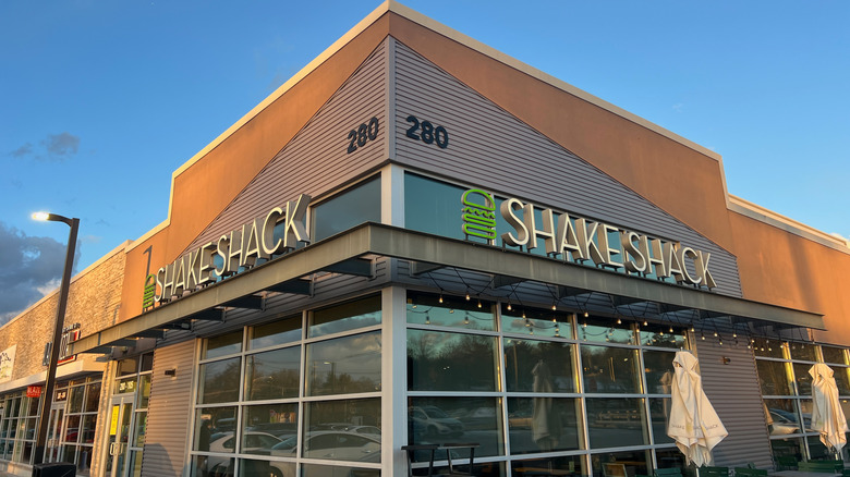 The exterior of Shake Shack with big windows and blue sky in the background