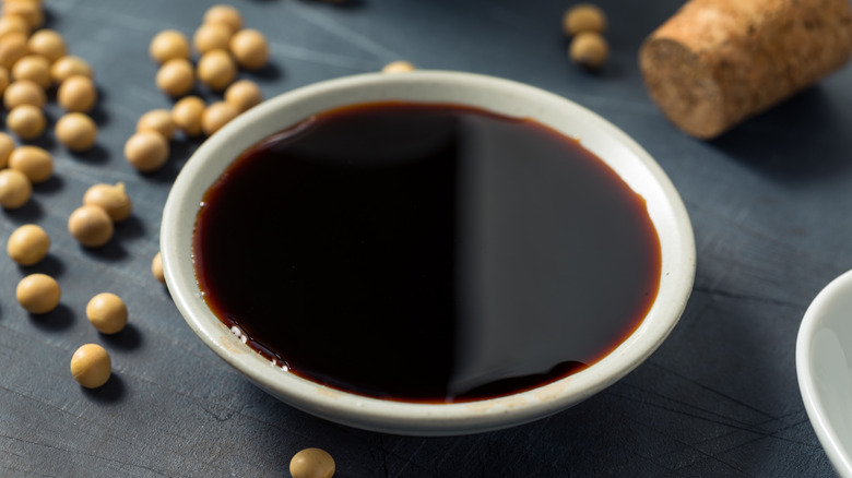 A bowl of organic tamari sauce next to soy beans