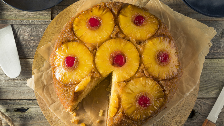 Pineapple upside down cake on parchment paper with missing slice