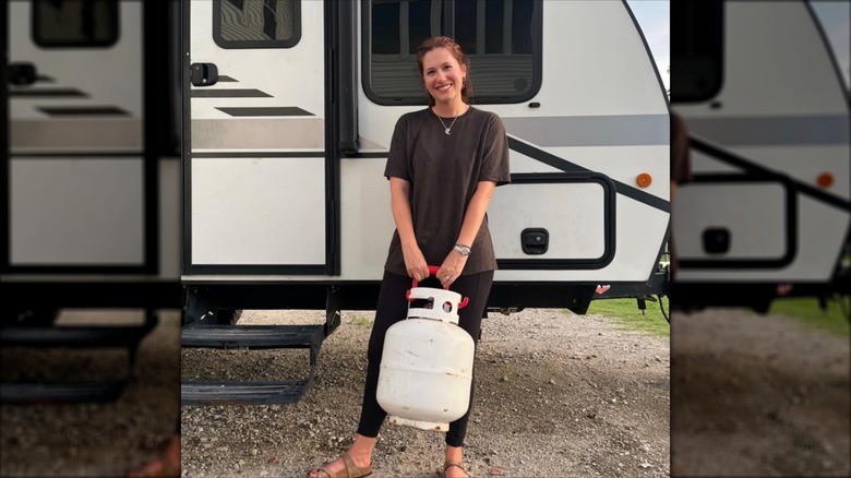 A camper holding a propane tank with a handle.