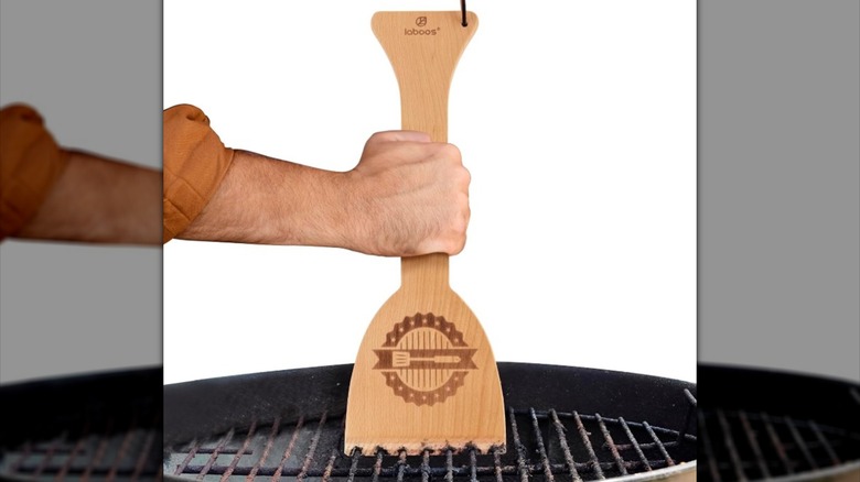 A wooden grill scraper with custom grooves.