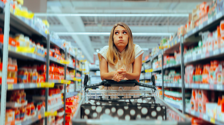 A female shopper looking worried behind a shopping cart