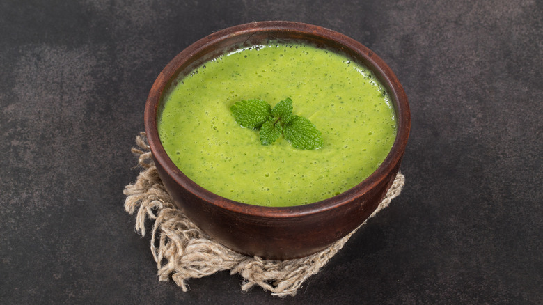 A small bowl of pea soup topped with fresh mint.