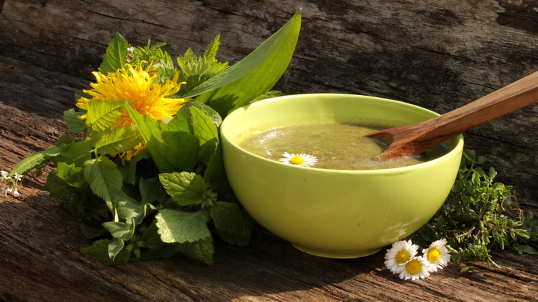 An herby bowl of soup has a side of dandelions.
