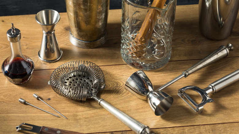 A variety of bar tools lie on a wooden counter