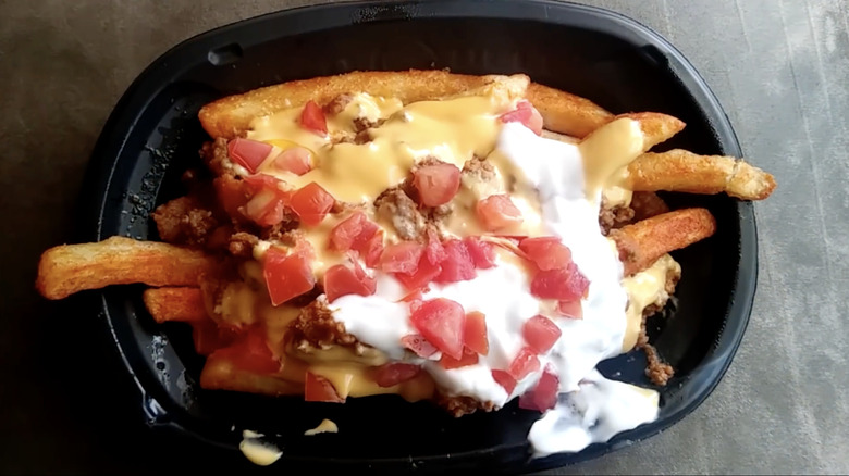 Taco Bell Fries Supreme Beef in a black container placed on a gray surface