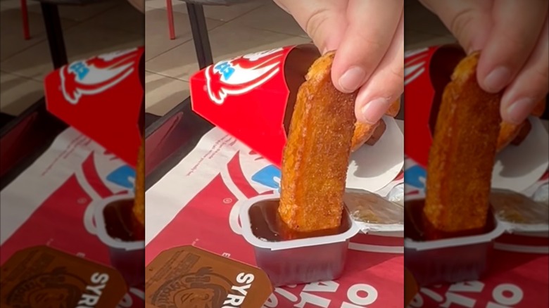 Wendy's Canada French toast stick dipped into maple syrup on a Wendy's tray