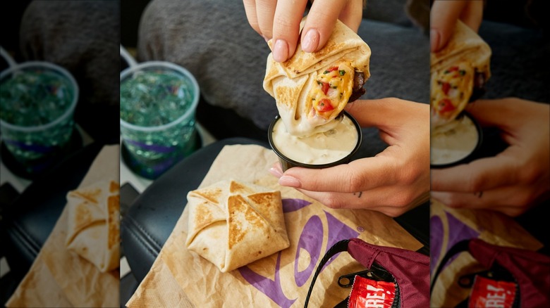 Taco Bell Steak & Queso Crunchwrap Sliders with one being dipped into a dipping sauce