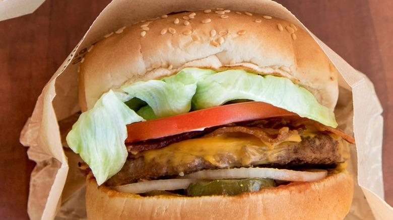 A&W Teen Burger in white paper wrapping placed on a brown table