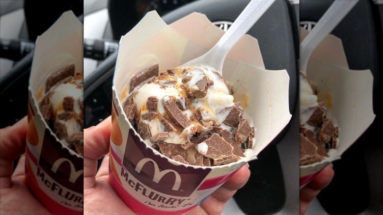 McDonald's Cadbury Creme Egg McFlurry with a white spoon held in front of a car steering wheel