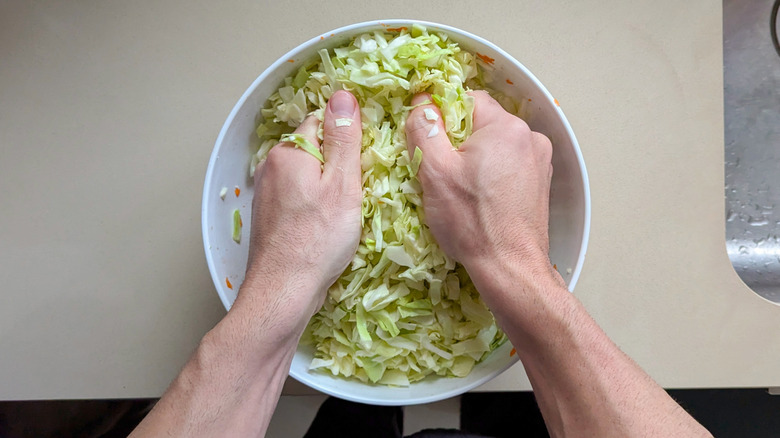 Male hands massaging a bowl of cabbage