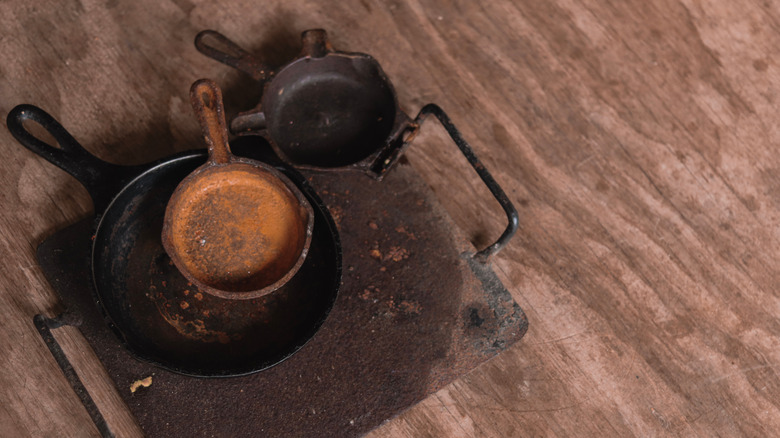 A selection of various rusty cast-iron skillets and a griddle