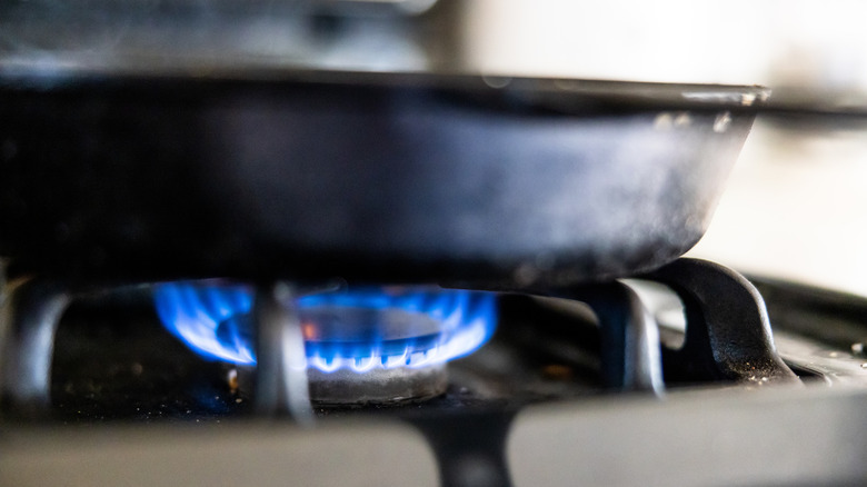 Close up of a cast-iron skillet over a lit gas stove burner