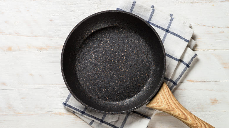 A cast-iron skillet with a wooden handle sits on a folded tea towel