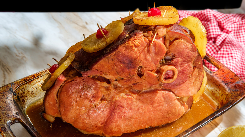Freshly baked ham with pineapple slices and cherries resting on kitchen counter