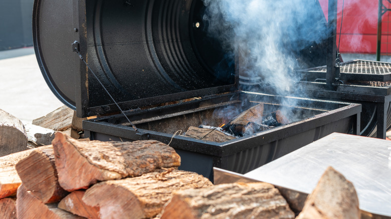 Pile of chopped wood alongside a barbecue smoker