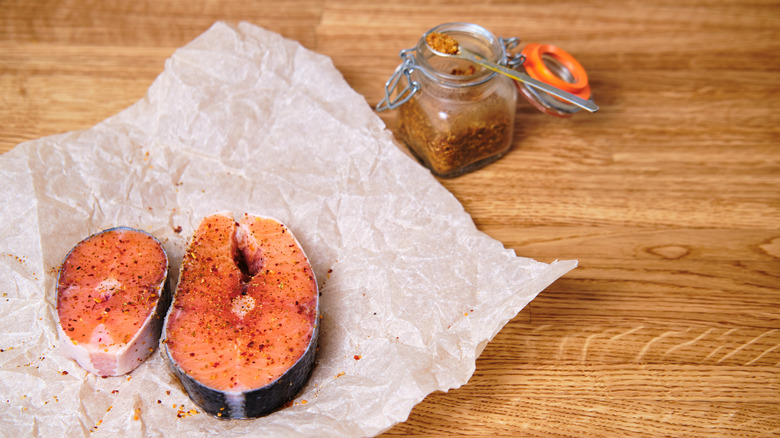 Sliced fish on parchment paper with seasoning