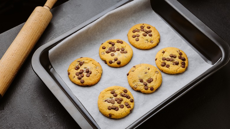 Parchment paper lined baking tray with chocolate chip cookies on it
