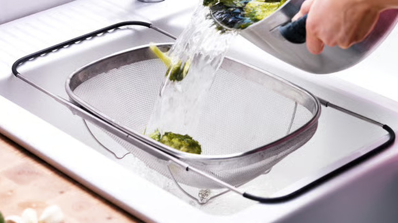 Person draining vegetables in the IDEALISK colander