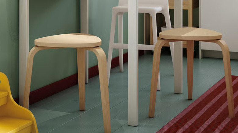 A chic wooden stool in front of a white modern sofa.