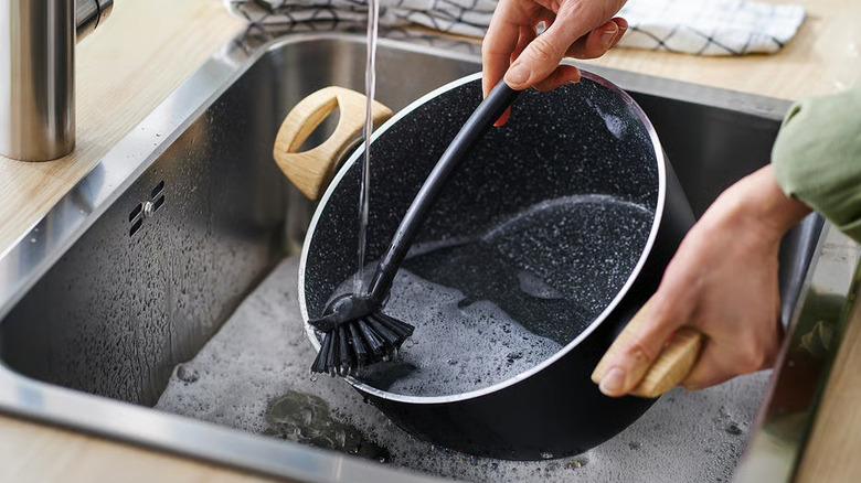 A RINNIG dish brush cleaning a pot