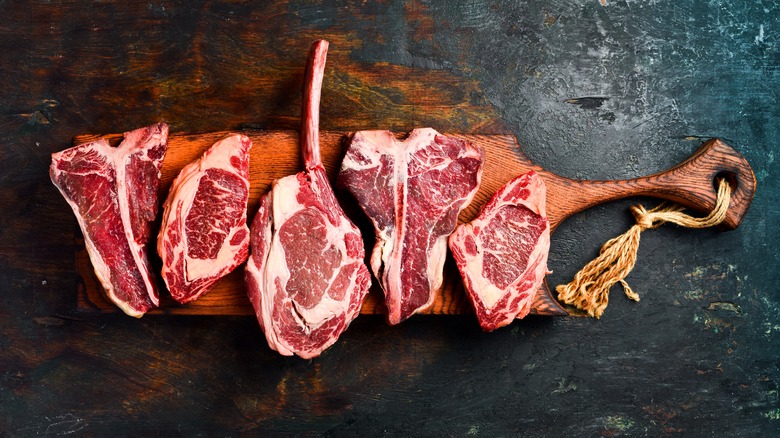 A selection of well-marbled raw steaks on a wooden board