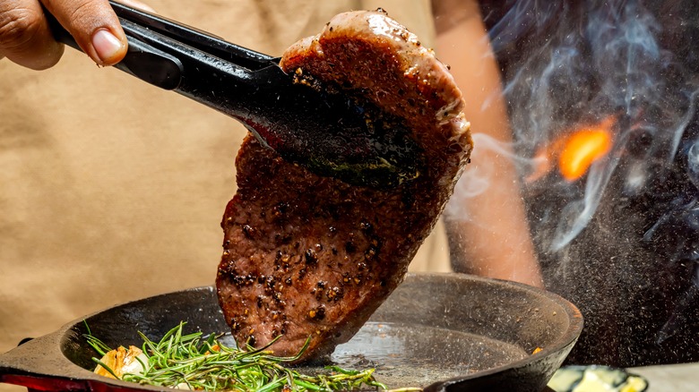 A chef flipping a steak in the pan