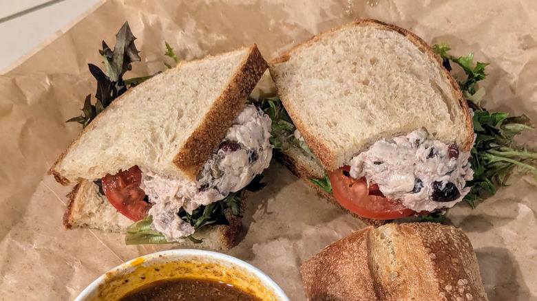 Panera Bread's cranberry walnut chicken salad on paper with soup and roll