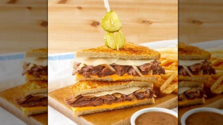 The double cheese pot roast dip on a plate with fries and pickle spear