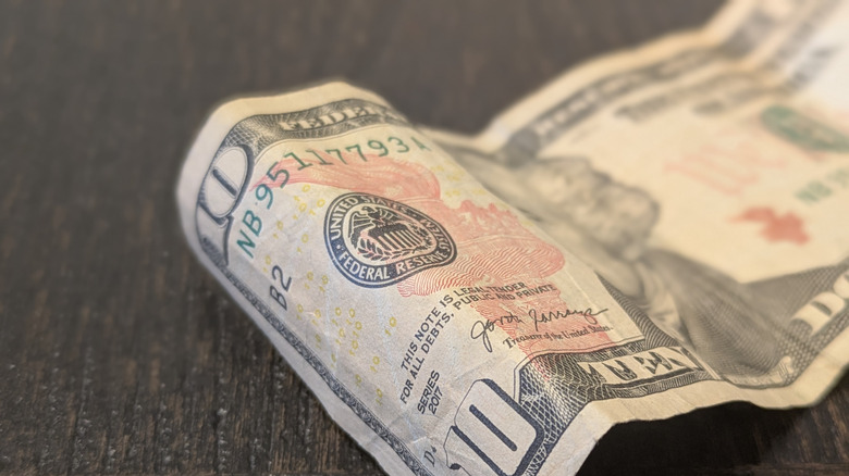 A crumpled ten dollar bill on a table