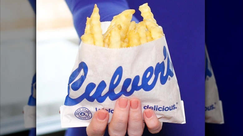 A person holds a bag of Culver's crinkle fries.