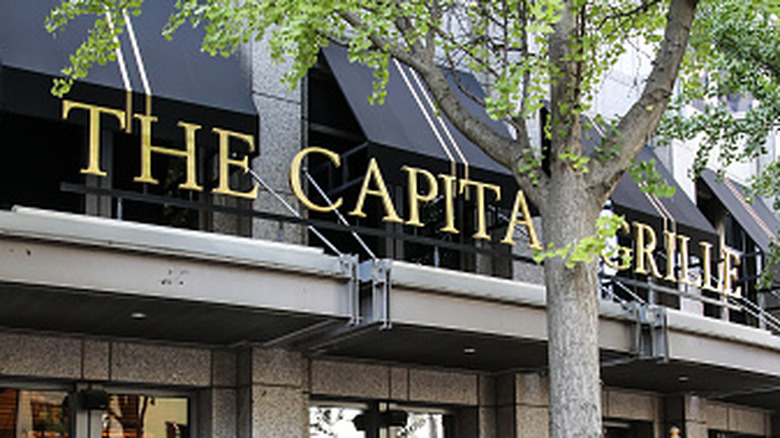 Exterior of The Capital Grille with a tree in front of the sign