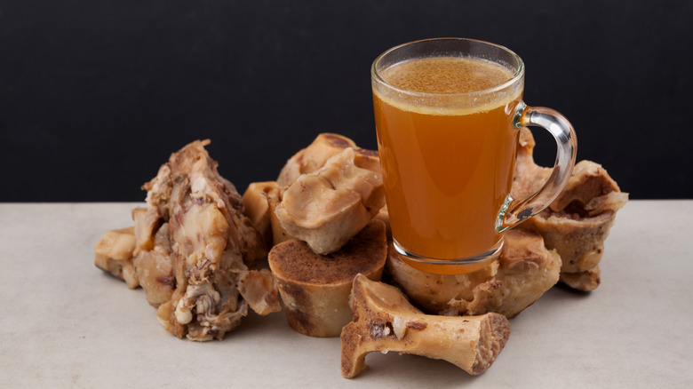 Bone broth in glass cup next to bone marrow