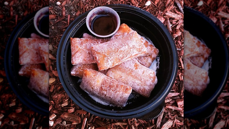 A to-go container of warm Italian donuts with raspberry sauce